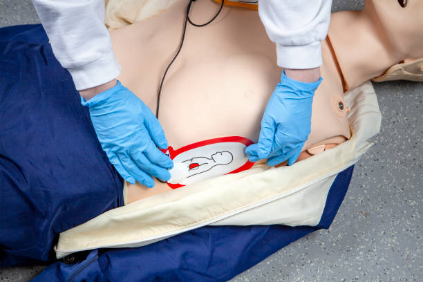 Performing a cardiopulmonary resuscitation (CPR) and using an AED (automated external defibrillator). Sticking the electrodes on the chest. Demonstration on a CPR dummy